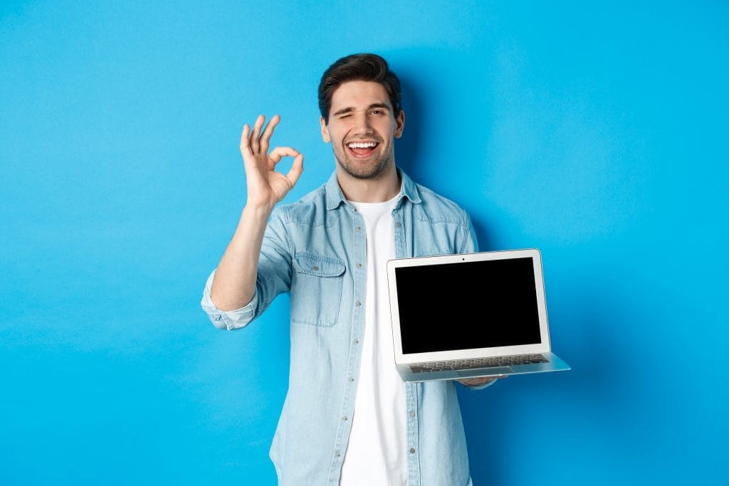 young man showing laptop screen okay sign approve like promo internet smiling satisfied standing blue background hangi sertifika ile iş bulunur